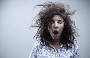 Image of a woman with messy hair, yawning