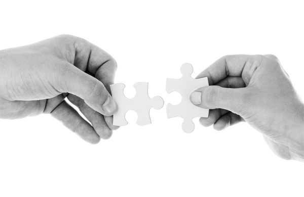 Image of hands holding 2 pieces of jigsaw puzzle