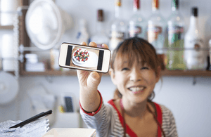 Image of cafe owner with video on phone screen