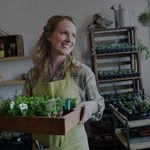 Smiling shop owner holding plants