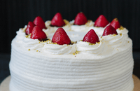 Delicious white cake with strawberries, cream and a pistachio crumb