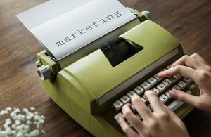 Green typewriter with the word "marketing" typed in a bold font.