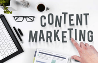 A desk "flatlay" with a hand pointing to the words "content marketing".