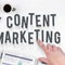 A desk "flatlay" with a hand pointing to the words "content marketing".