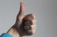Thumbs up with a smiley face drawn on the thumb.