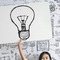 Girl holding up a light bulb sign