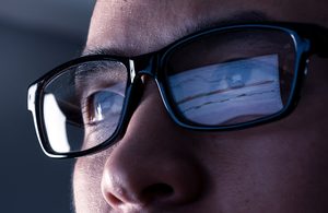 Image of person wearing glasses with screen reflection