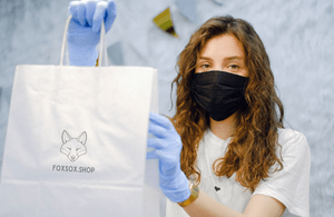 Woman wearing a mask and holding a boutique shopping bag