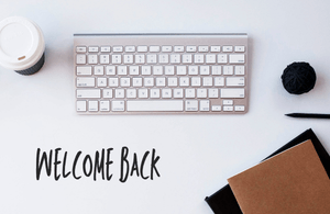 Keyboard on a desk with a note saying welcome back