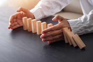 Image of some hands stopping wooden blocks being knocked down