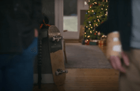A frame from John Lewis's Christmas ad: a skateboard leaning against a sofa with a Christmas tree in the background