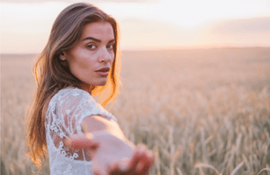 A girl in a corn field, holding out her hand